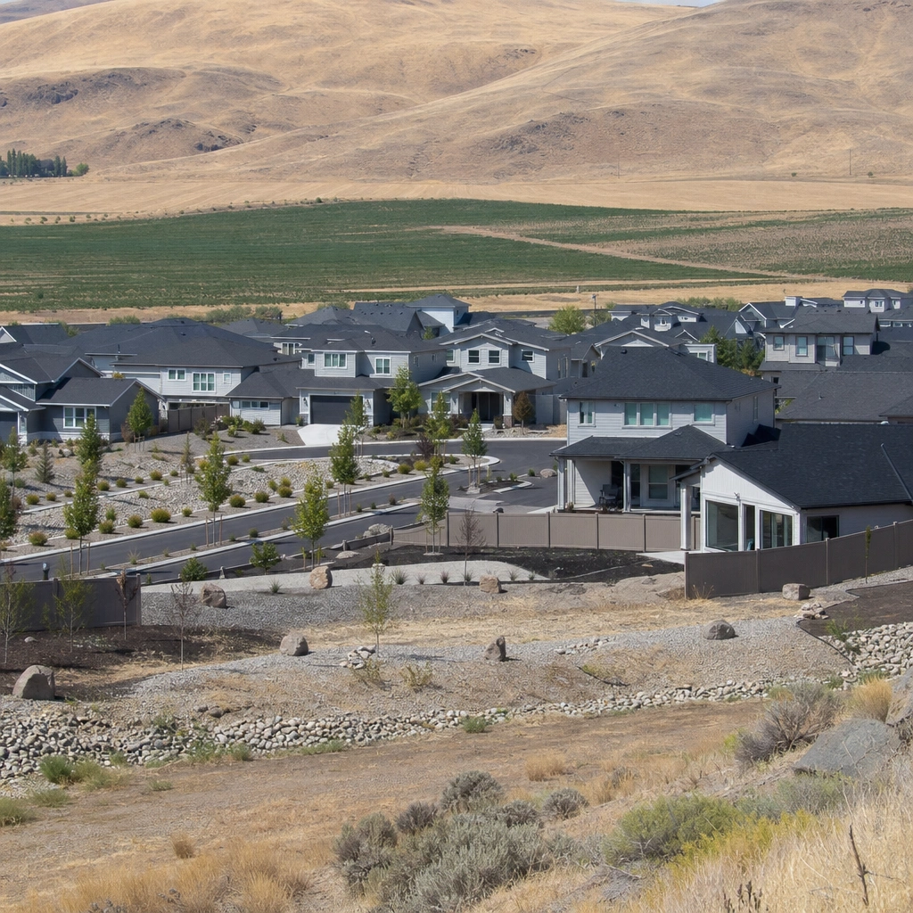 A new Tri-Cities housing development built up against farm fields and bare hills